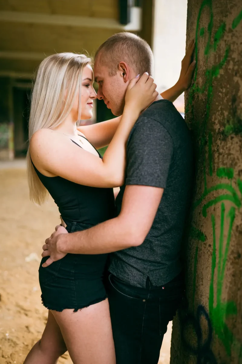 Laura und Emilis - Urbane Location in Plagwitz Paarfotograf Leipzig – Nahaufnahme Paar an Graffiti-Betonsäule, Stirnen nah beieinander, sinnlicher Moment