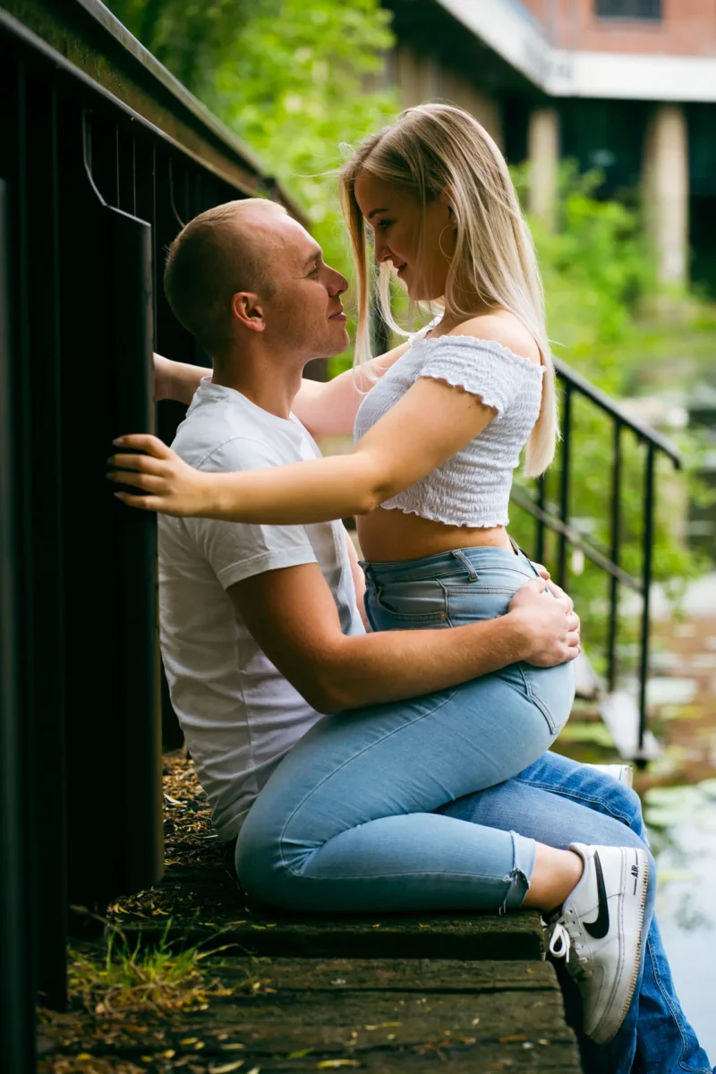 Laura und Emilis - Urbane Location in Plagwitz Paarfotograf Leipzig Plagwitz – Reiterpose am Stelzenhaus-Steg, Paar lächelt sich an mit Kanal im Hintergrund