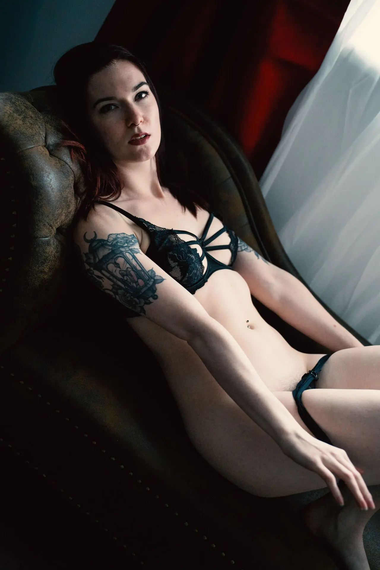 Frau in schwarzer Spitzen-Dessous lehnt auf der Couch und blickt direkt in die Kamera – Akt Boudoir Fotoshooting Leipzig