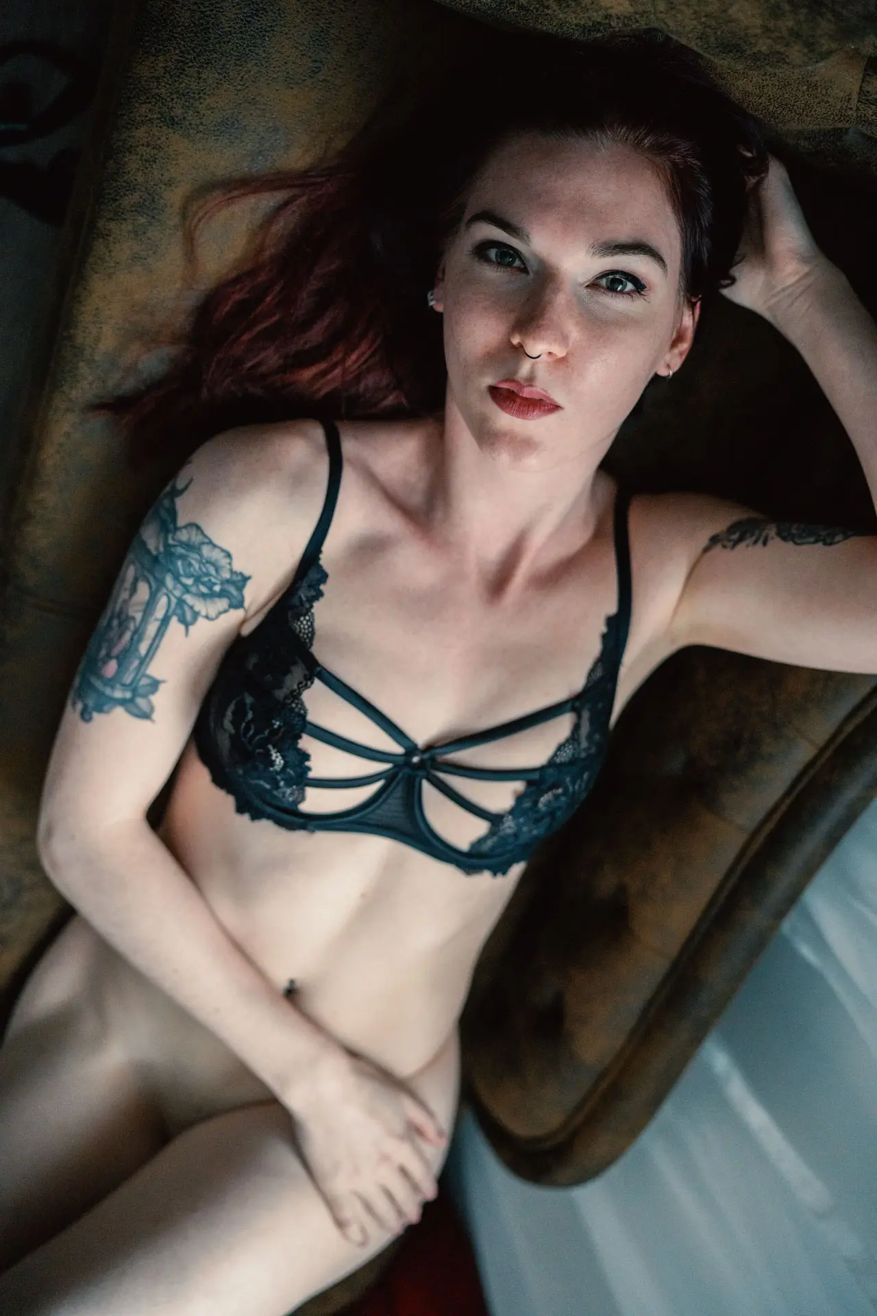 Frau in schwarzem Spitzen-BH liegt auf der Couch und blickt aus der Vogelperspektive intensiv in die Kamera – verdeckter Akt Boudoir Fotoshooting Leipzig
