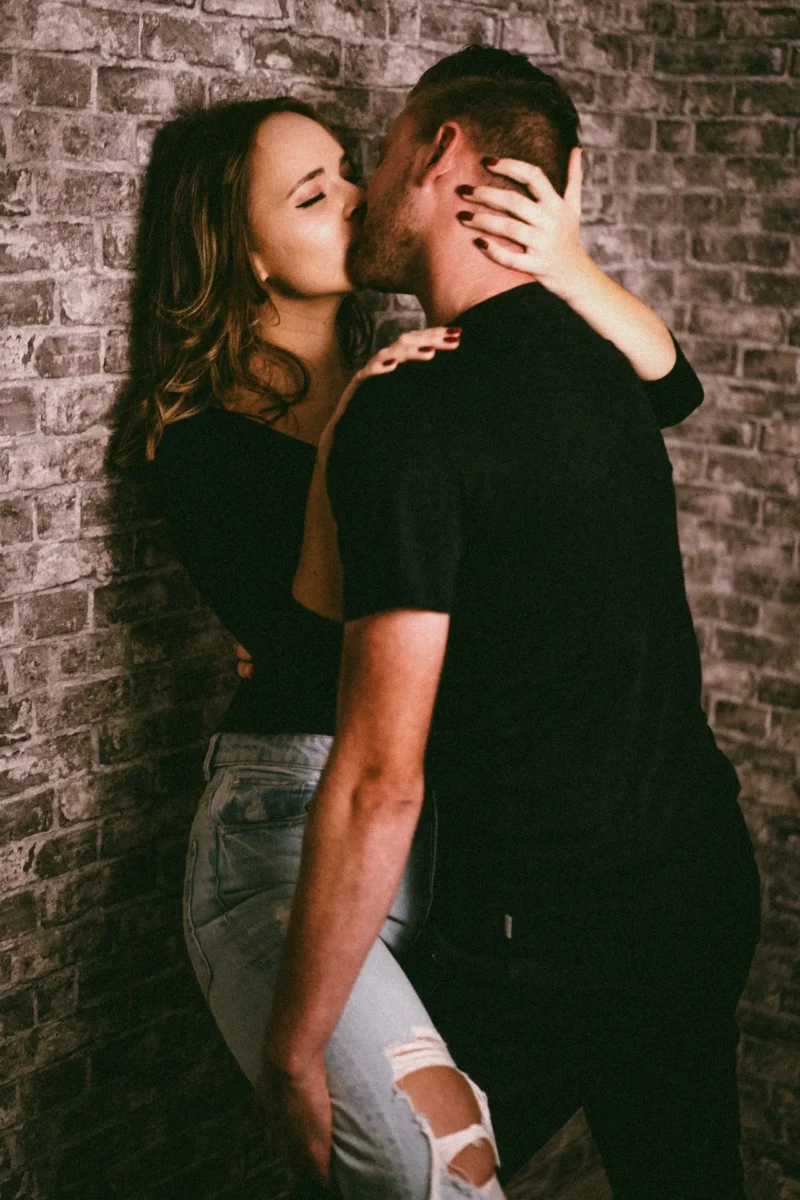 Marie und Benny - süß und sexy - junge Liebe halt Paarfotograf Leipzig – leidenschaftlicher Kuss an Backsteinwand im Fotostudio Traumgarten