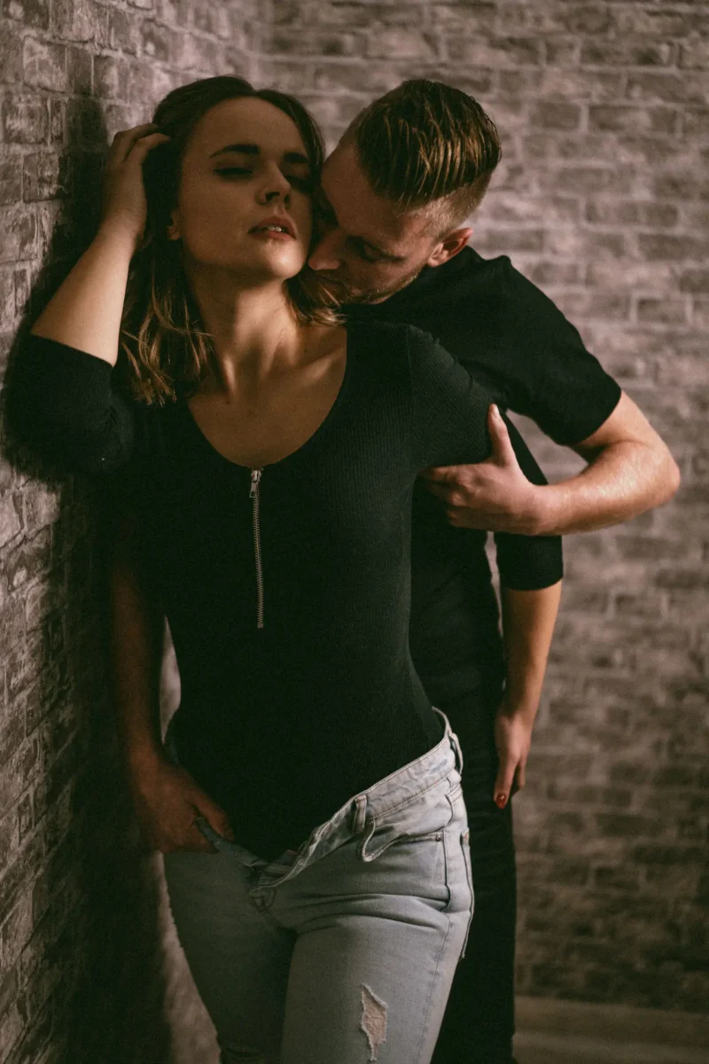 Marie und Benny - süß und sexy - junge Liebe halt Paarshooting Leipzig – Mann küsst Frau sinnlich am Hals, schwarzer Body, Traumgarten Studio