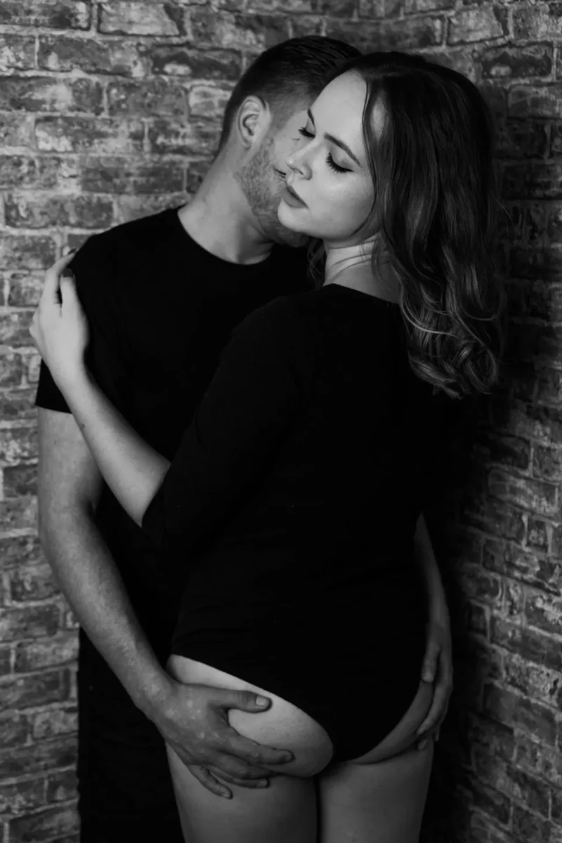 Marie und Benny - süß und sexy - junge Liebe halt Paarfotograf Leipzig – sinnliche Umarmung an Backsteinwand, Schwarz-Weiß, Traumgarten Studio