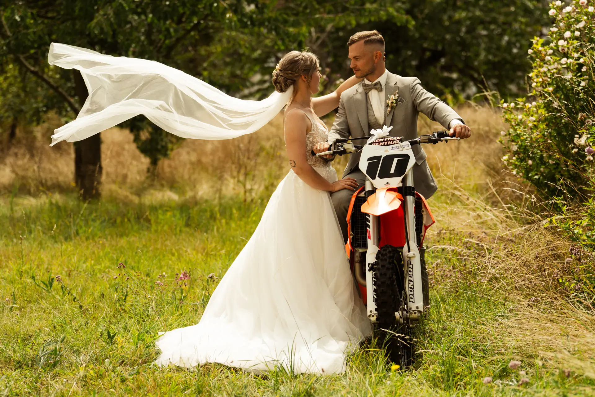 Brautpaar mit wehendem Schleier auf Motocross-Maschine